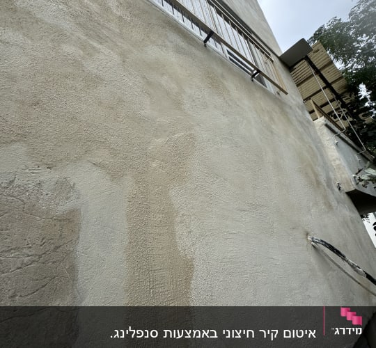 קיר טיח עם חלון סורגי מתכת